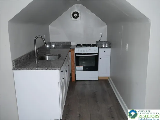 a kitchen with granite countertop a stove top oven and sink