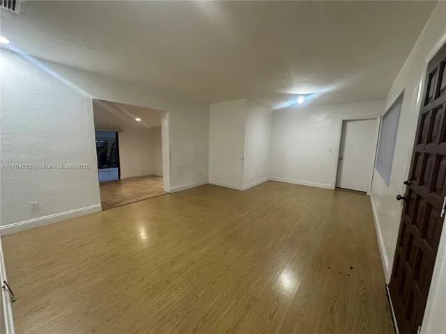 an empty room with wooden floor and entrance