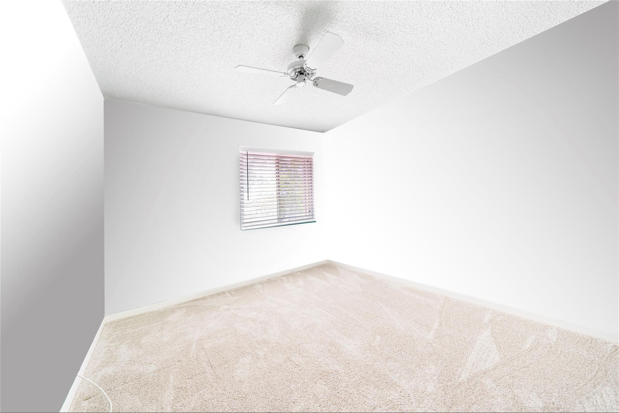 10423 Boca Springs Drive Boca Raton, FL 33428 - Photo 17 of 64 an empty room with a chandelier fan and windows