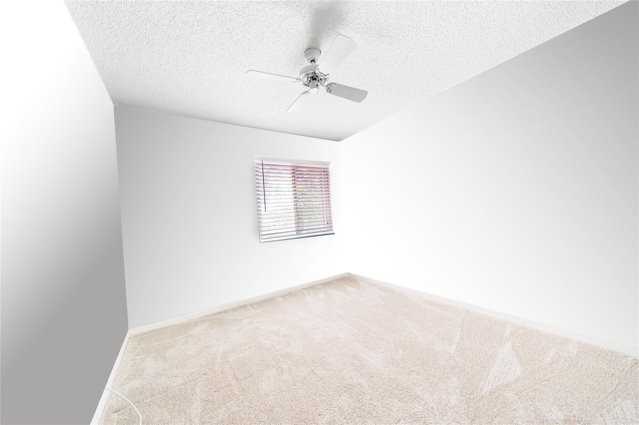 10423 Boca Springs Drive Boca Raton, FL 33428 - Photo 18 of 64 an empty room with a chandelier fan and windows