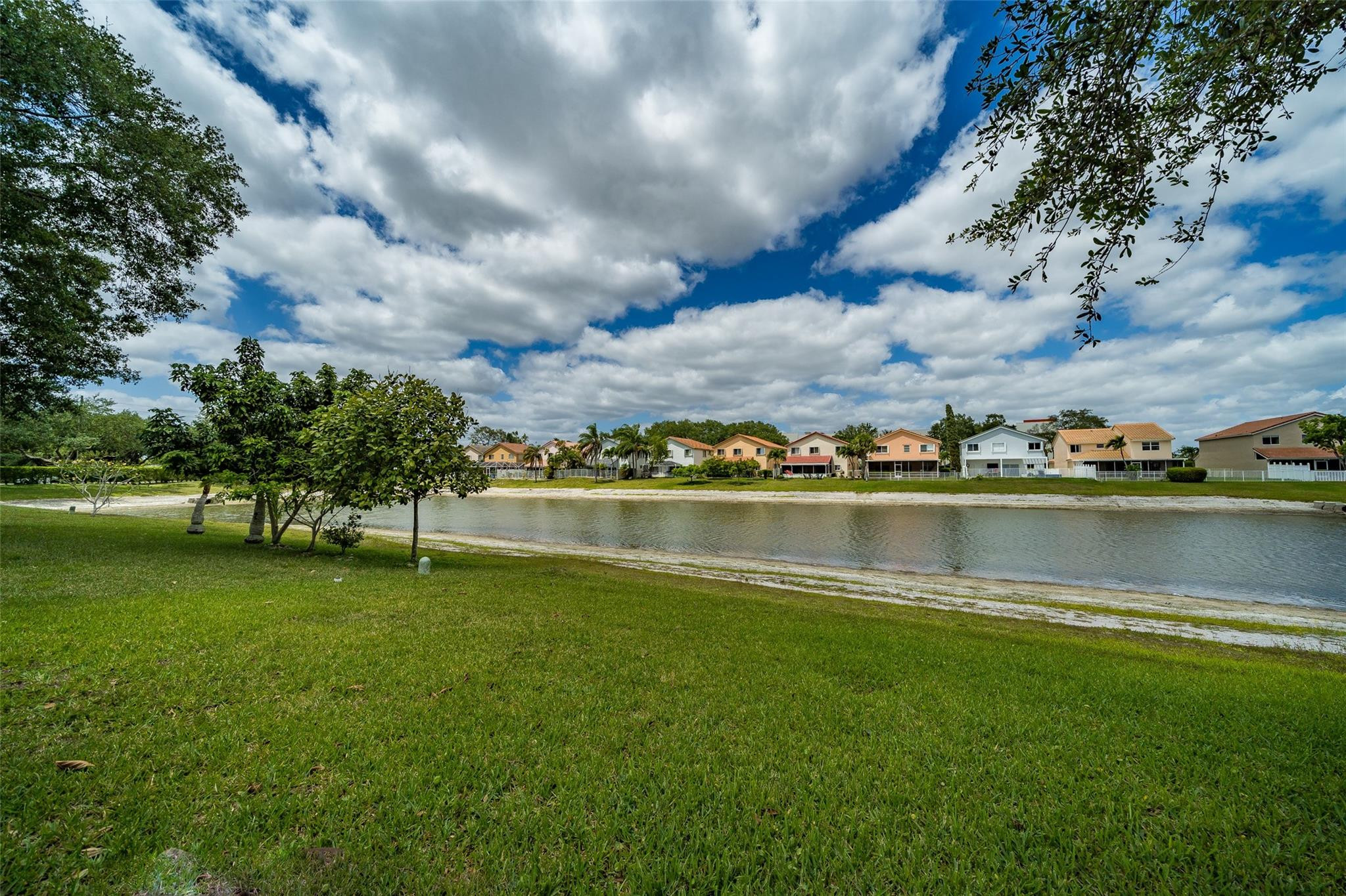 10423 Boca Springs Drive Boca Raton, FL 33428 - Photo 2 of 64 a view of a lake with houses in the back
