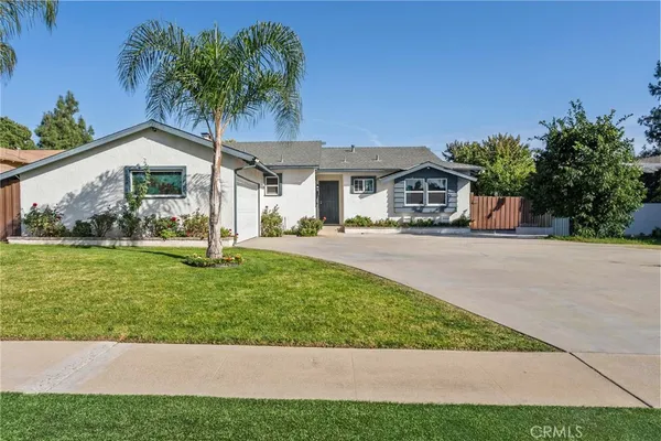 a front view of a house with a yard and potted plants