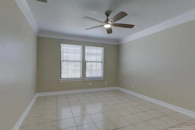 an empty room with chandelier fan and windows