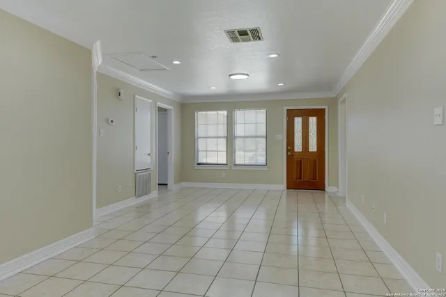 a view of an empty room with window and chandelier