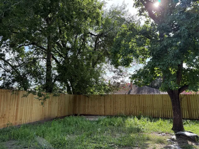 a view of backyard with potted plants and wooden fence