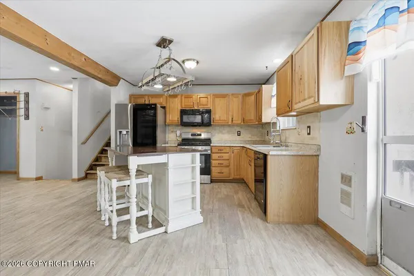 a kitchen with stainless steel appliances granite countertop a stove top oven a sink dishwasher a dining table and chairs with wooden floor