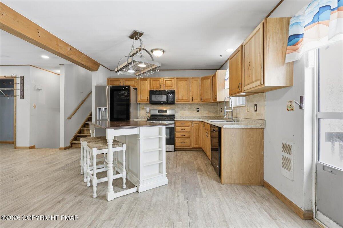 199 Magic Mountain Road Henryville, PA 18332 - Photo 13 of 74 a kitchen with stainless steel appliances kitchen island granite countertop a refrigerator a stove a microwave oven a sink with island and chairs with wooden floor