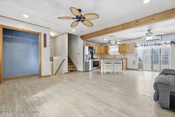 a kitchen with stainless steel appliances kitchen island granite countertop a refrigerator a stove a microwave oven a sink with island and chairs with wooden floor