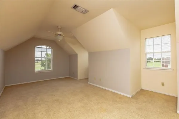 an empty room with windows and ceiling fan