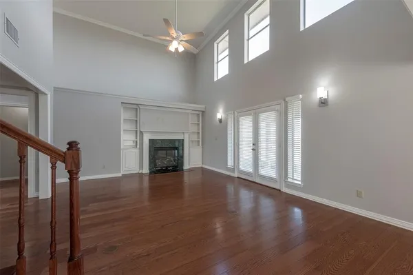 an empty room with wooden floor fireplace and windows