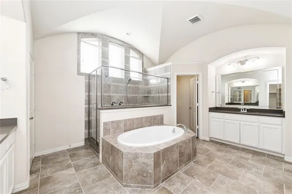 a bathroom with a tub a mirror and a shower