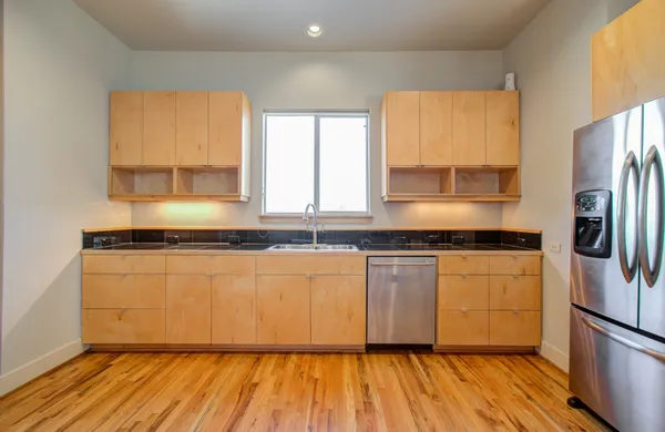a kitchen with stainless steel appliances granite countertop a refrigerator a sink dishwasher a stove and white countertops with wooden floor