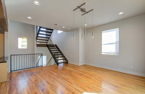 a view of an empty room with wooden floor stairs and a window