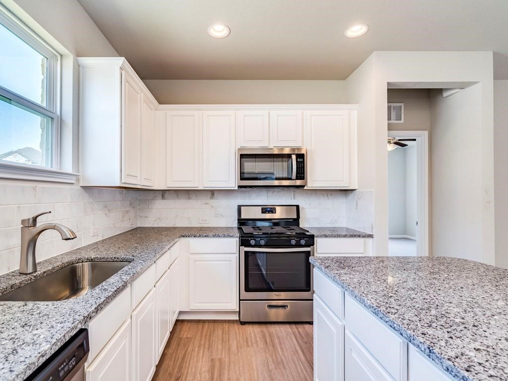 4210 Birdwatch Loop, Unit 2 Pflugerville, TX 78660 - Photo 13 of 31 Culinary dreams come alive in this kitchen, featuring sleek granite counters and stainless steel appliances.