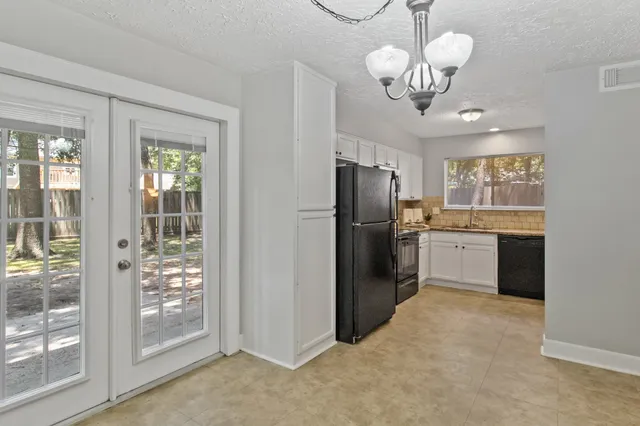 a kitchen with stainless steel appliances granite countertop a refrigerator a stove a sink dishwasher a refrigerator and a chandelier