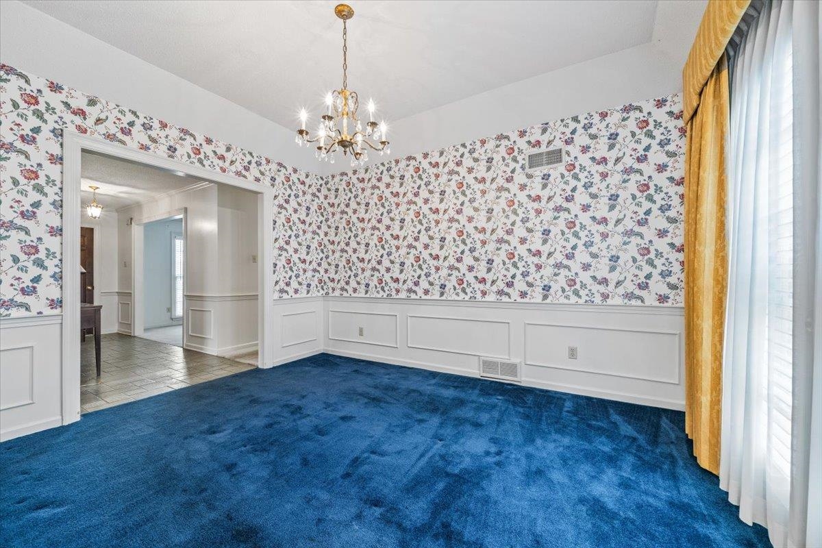 2587 McVay Road Memphis, TN 38119 - Photo 11 of 35 Unfurnished dining area with wallpapered walls, hanging lights, wainscoting, dark colored carpet, and a decorative wall