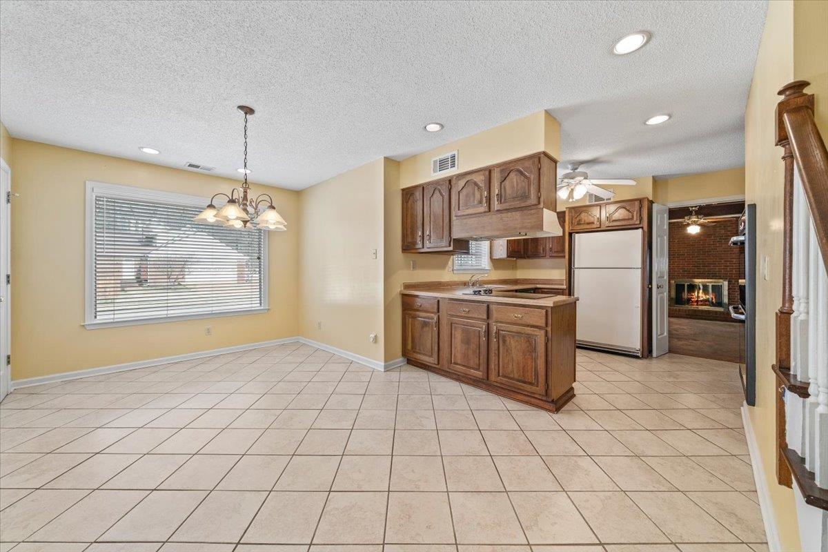2587 McVay Road Memphis, TN 38119 - Photo 15 of 35 Kitchen featuring freestanding refrigerator, a textured ceiling, a chandelier, light tile patterned floors, and a ceiling fan
