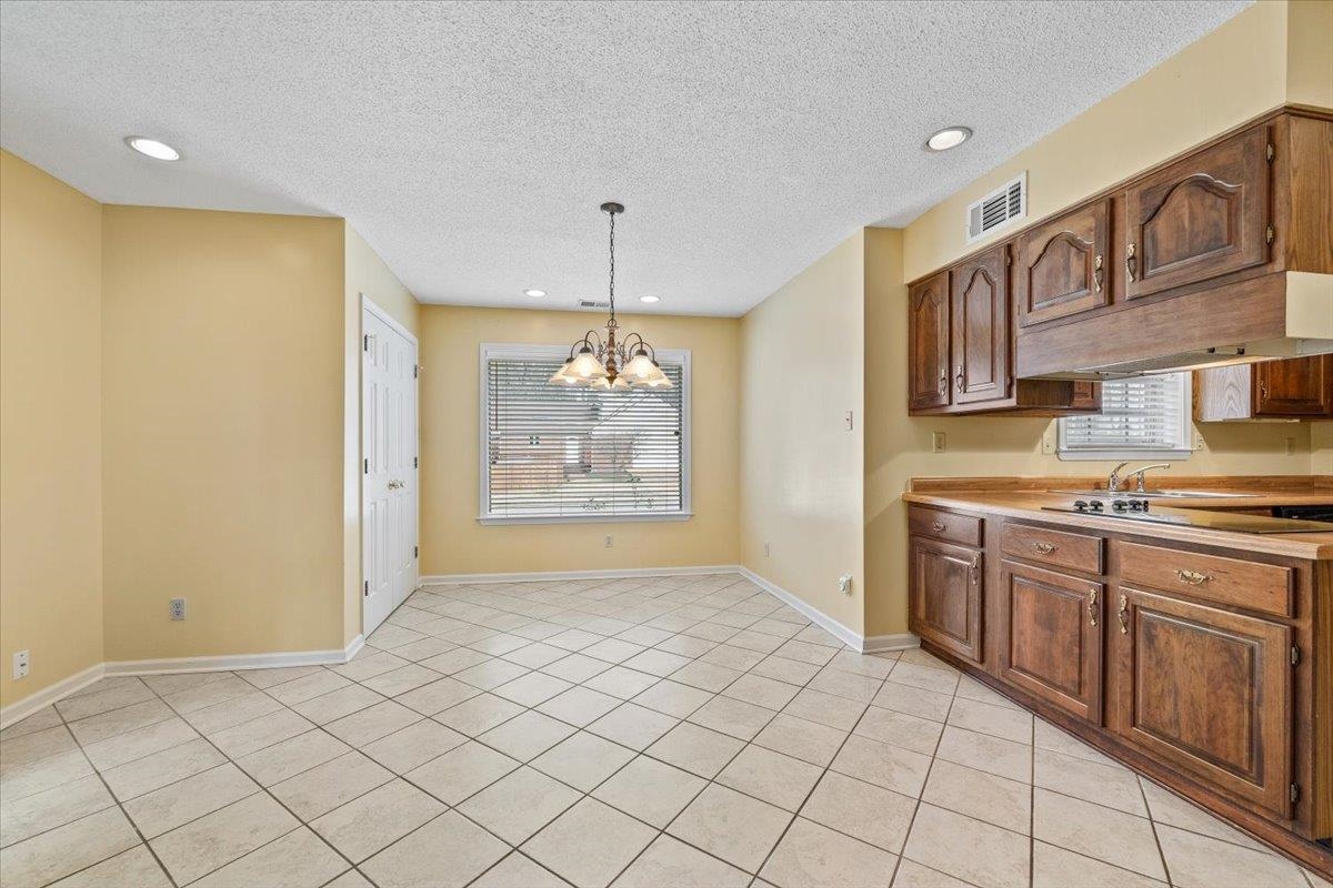 2587 McVay Road Memphis, TN 38119 - Photo 16 of 35 Kitchen featuring hanging lights, light countertops, a textured ceiling, light tile patterned floors, and wood finish cabinetry