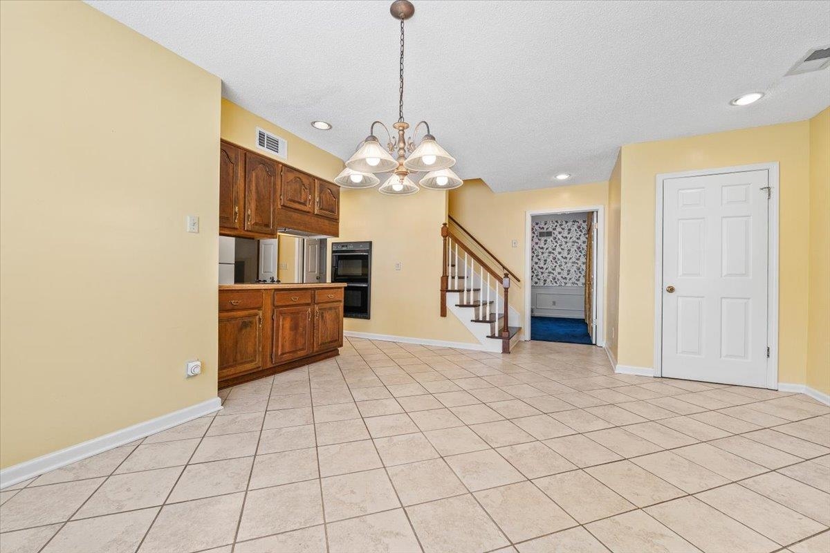2587 McVay Road Memphis, TN 38119 - Photo 17 of 35 Kitchen featuring hanging lights, wood finish cabinetry, a textured ceiling, light tile patterned flooring, and light countertops