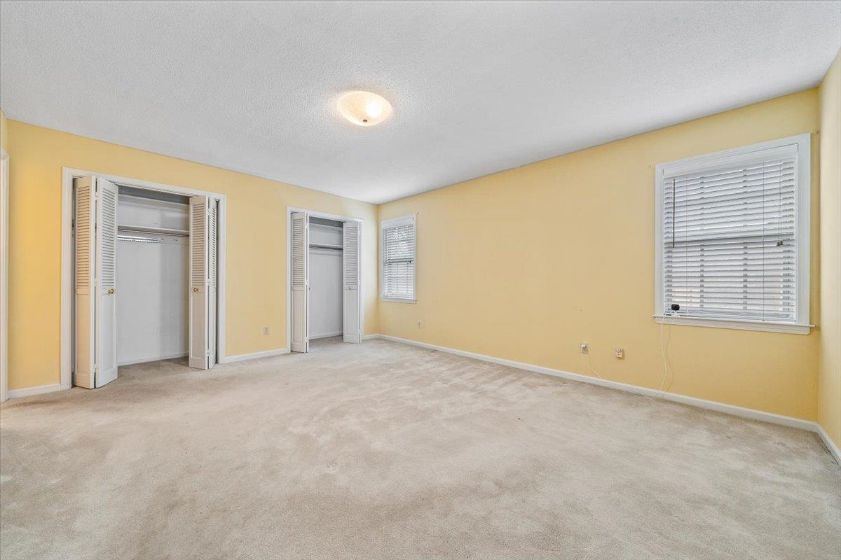 2587 McVay Road Memphis, TN 38119 - Photo 19 of 35 Primary bedroom featuring two closets, light colored carpet, a textured ceiling, and multiple windows; door to patio