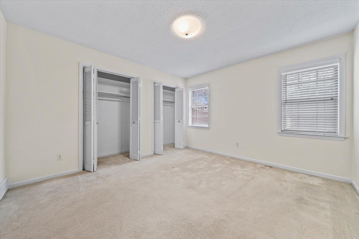 2587 McVay Road Memphis, TN 38119 - Photo 22 of 35 Unfurnished bedroom featuring multiple closets, a textured ceiling, light colored carpet, and multiple windows