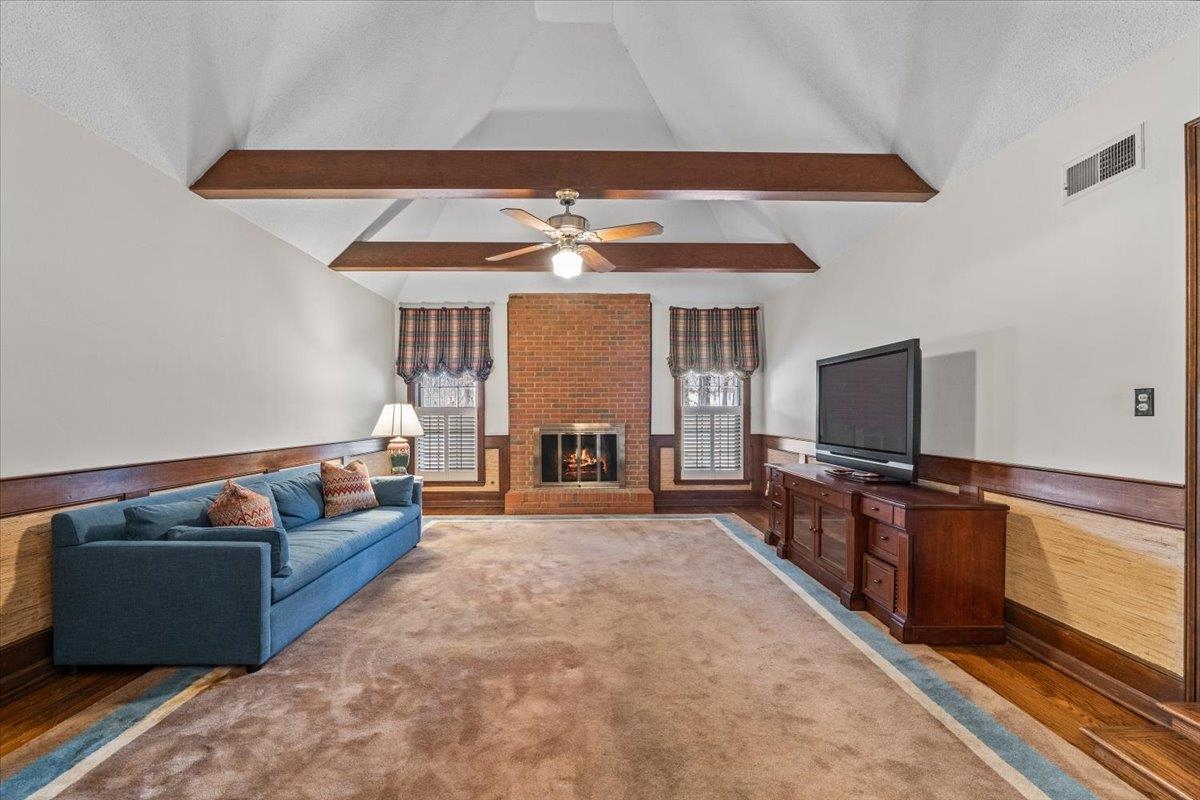 2587 McVay Road Memphis, TN 38119 - Photo 7 of 35 Living area featuring wainscoting, a fireplace, wood walls, lofted ceiling with beams, and wood finished floors
