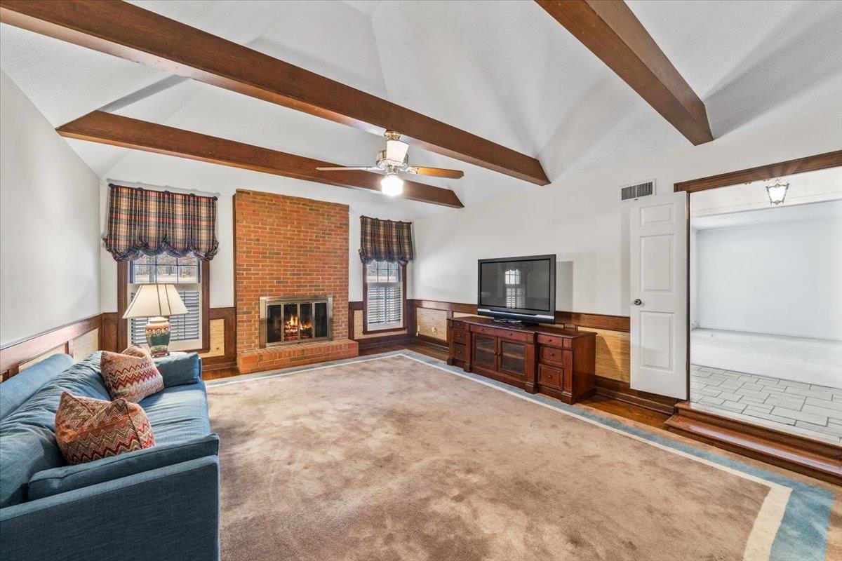 2587 McVay Road Memphis, TN 38119 - Photo 8 of 35 Living area featuring a wainscoted wall, a fireplace, vaulted ceiling with beams, carpet floors, and ceiling fan
