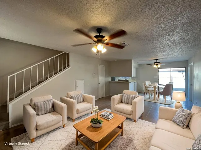 a living room with furniture a ceiling fan and a rug