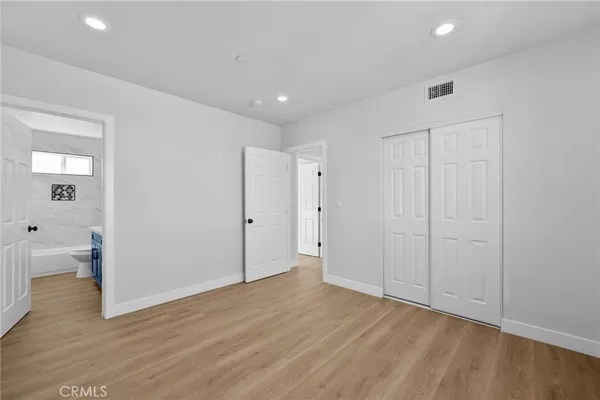 a view of an empty room with wooden floor and a bathroom