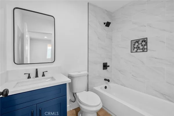 a bathroom with a bathtub shower sink vanity mirror and toilet