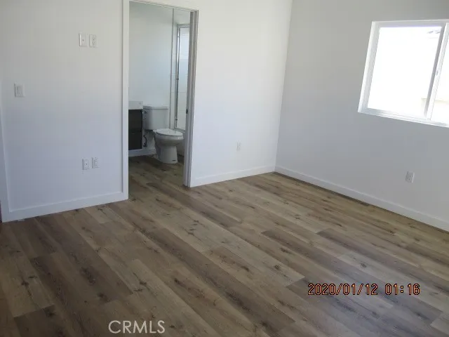 an empty room with wooden floor and a bathroom