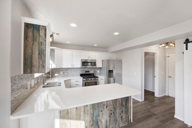 1440 West 100 South Virgin, UT 84779 - Photo 15 of 45 Kitchen featuring white cabinetry, stainless steel appliances, a tile backsplash, light countertops, and wood-finish flooring
