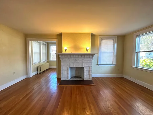 wooden floor fireplace and windows in an empty room