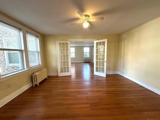 a view of an empty room with wooden floor and a window