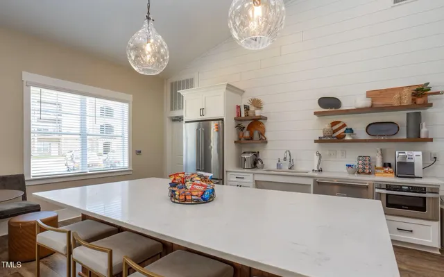 a kitchen with stainless steel appliances a table and chairs in it