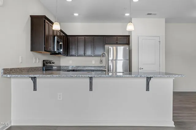 a kitchen with stainless steel appliances granite countertop a sink a stove and a refrigerator