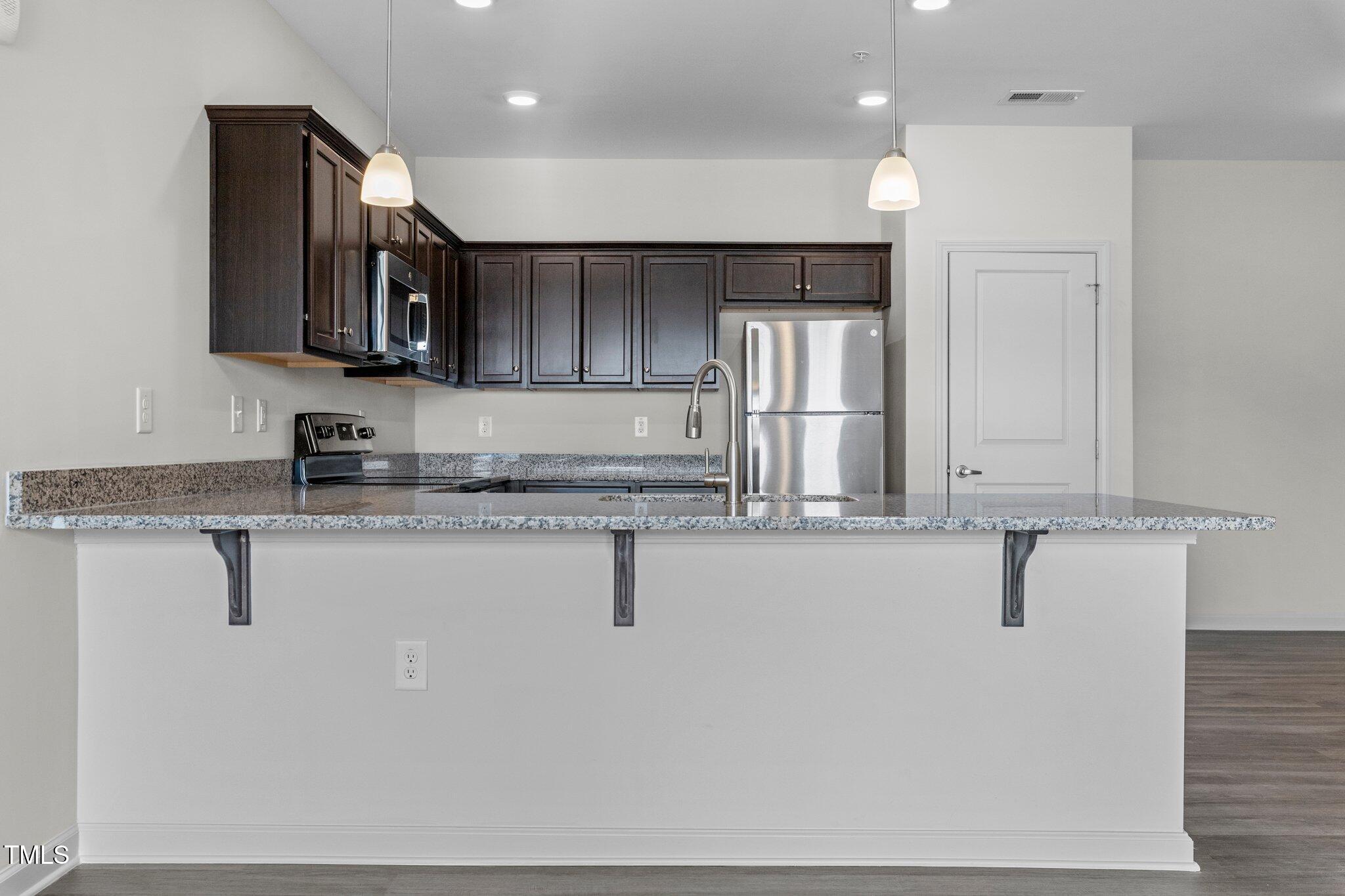 170 Grove Circle, Unit 302 Lillington, NC 27546 - Photo 9 of 28 a kitchen with stainless steel appliances granite countertop a sink a stove and a refrigerator