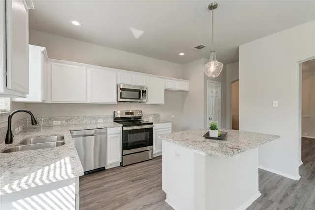a kitchen with stainless steel appliances granite countertop a sink a stove and a wooden floors