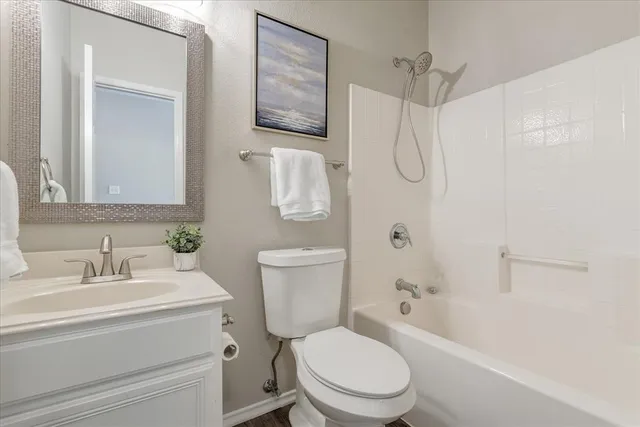 a bathroom with a toilet sink vanity granite and shower
