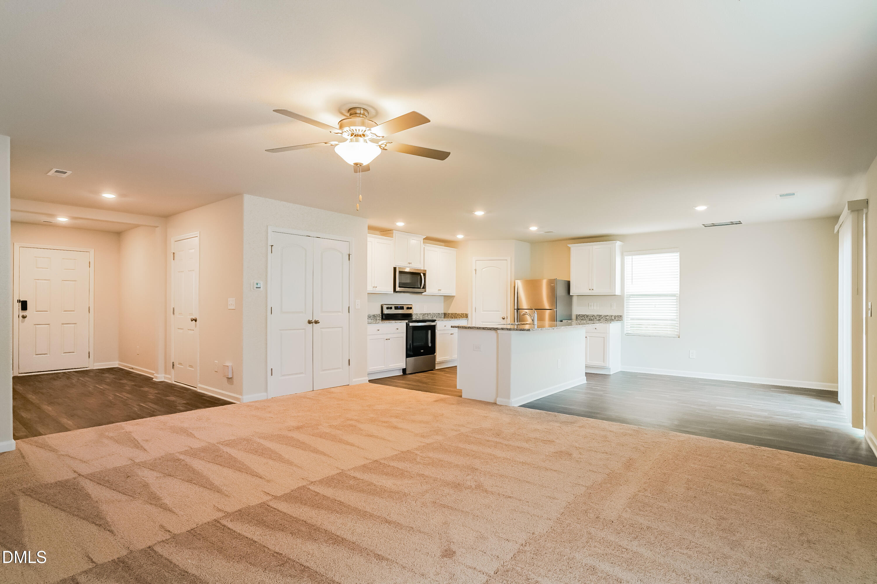 741 Cider Ml Way Zebulon, NC 27597 - Photo 2 of 17 a view of a kitchen with kitchen island a sink stainless steel appliances wooden floor and a counter top space