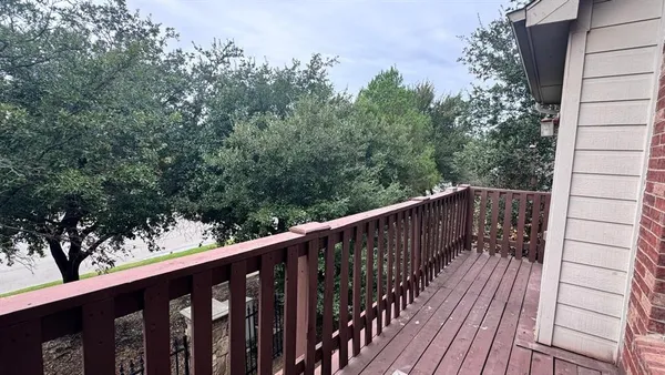 a balcony with wooden floor and trees in the back
