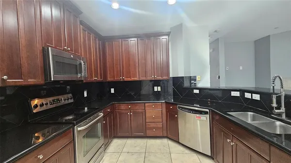 a kitchen with granite countertop a sink a stove and cabinets