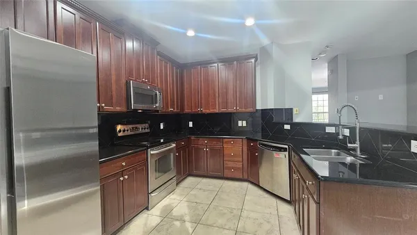 a kitchen with stainless steel appliances granite countertop a sink a stove and a refrigerator