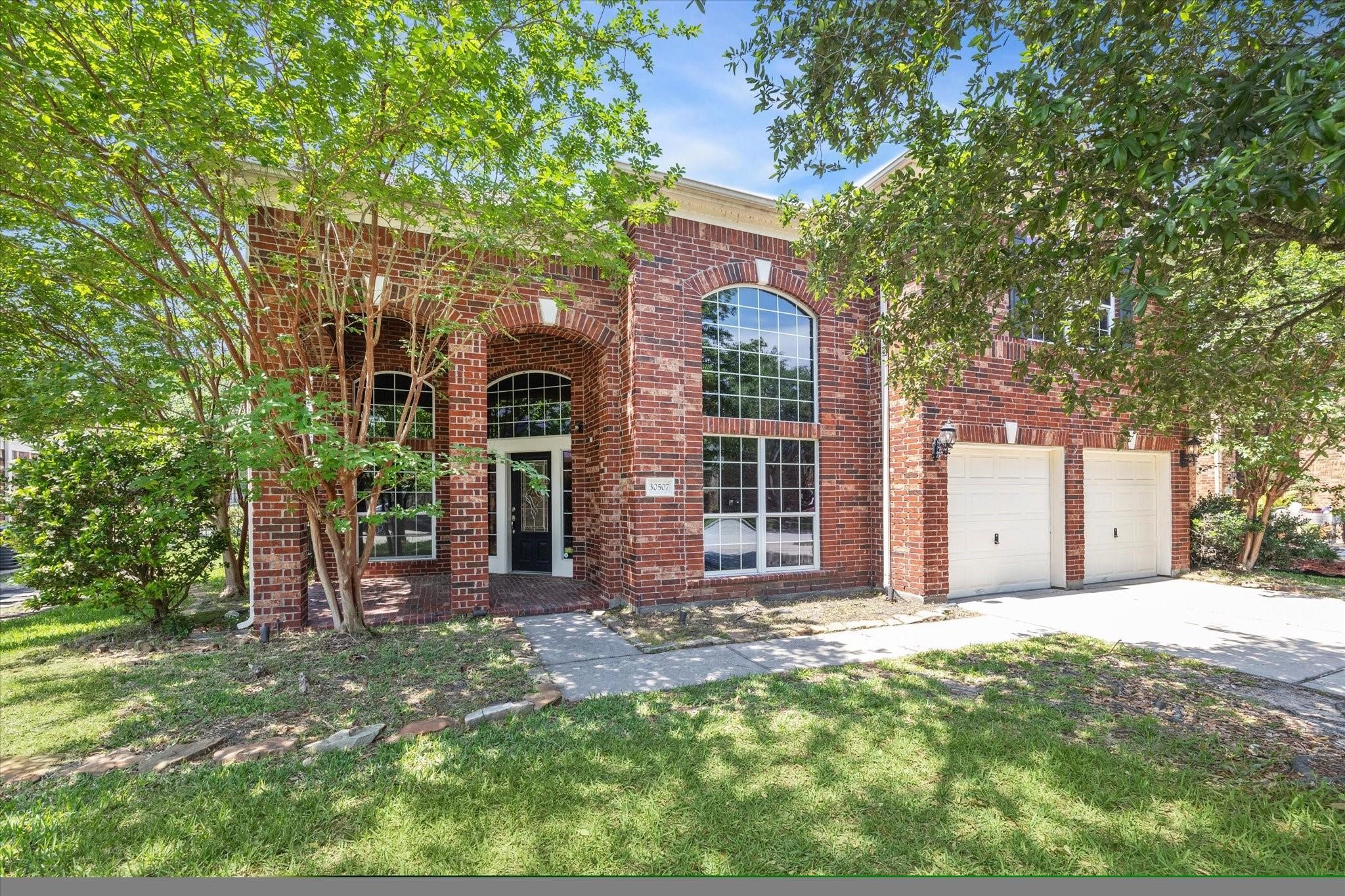 30507 Russell Point Drive Spring, TX 77386 - Photo 3 of 33 This beautiful two-story home features large arched windows and two-car garage. It is surrounded by lush greenery, providing a welcoming and serene entrance.