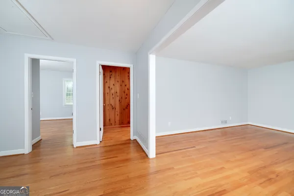 a view of an empty room with wooden floor and closet
