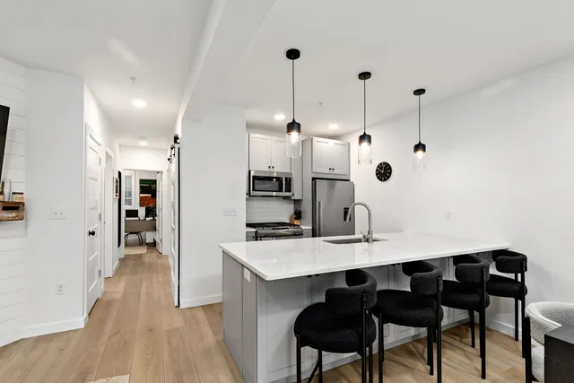 a kitchen with stainless steel appliances kitchen island granite countertop a table chairs and a refrigerator