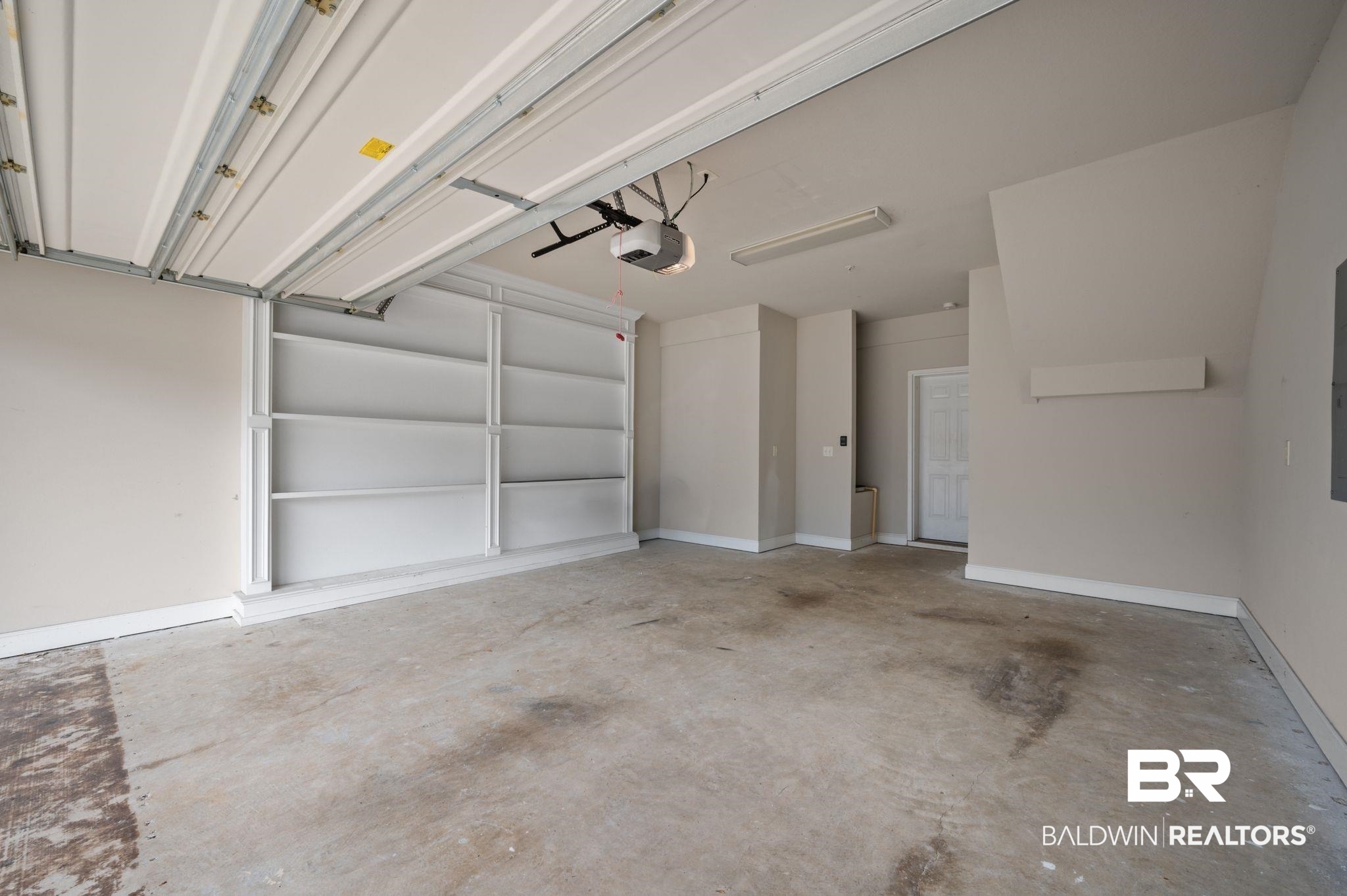 6903 Spaniel Drive, Unit B Spanish Fort, AL 36527 - Photo 23 of 28 Garage featuring a garage door opener and baseboards