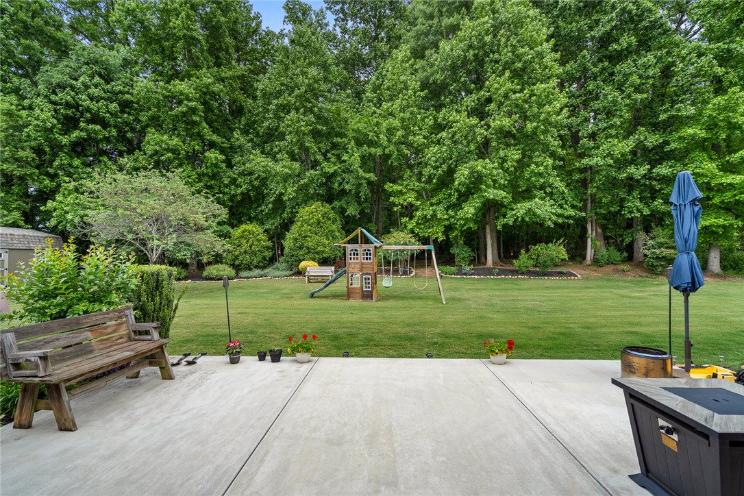 128 Baybrooke Lane Anderson, SC 29621 - Photo 35 of 37 A spacious backyard retreat features a well-maintained lawn and a private playground, bordered by mature trees.