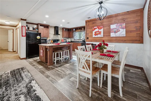 a kitchen with stainless steel appliances kitchen island granite countertop a table chairs and a refrigerator