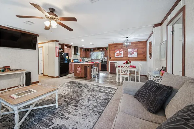 a living room with furniture a flat screen tv and kitchen view